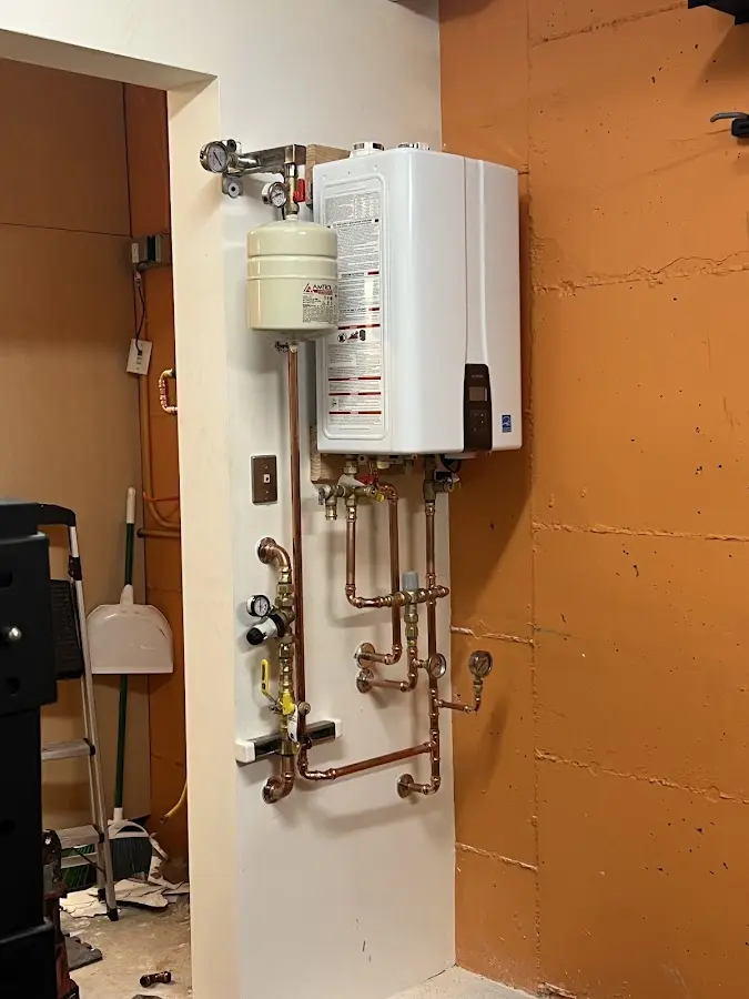 Plumbing technician inspecting water heater connections in Andrews